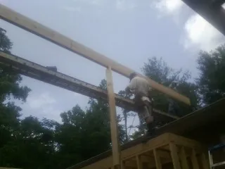 Carpenter setting a ridge beam over a new addition frame — Ice Dam Removal by Roofing Brothers in Waukee