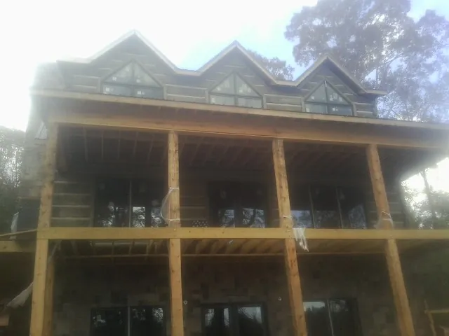 Dormers and porch framing on a large log home under construction — Roof Coating work by our crew in Waukee
