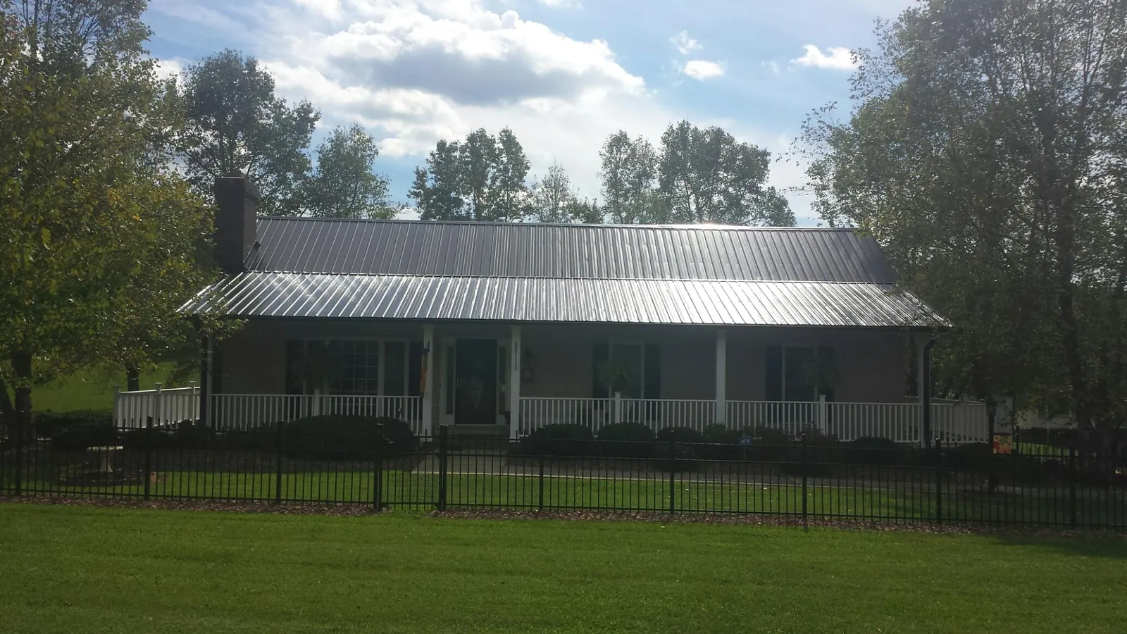 Gray metal roof on a brick ranch with a full width front porch — Gutter Guard Installation work by our crew in Waukee