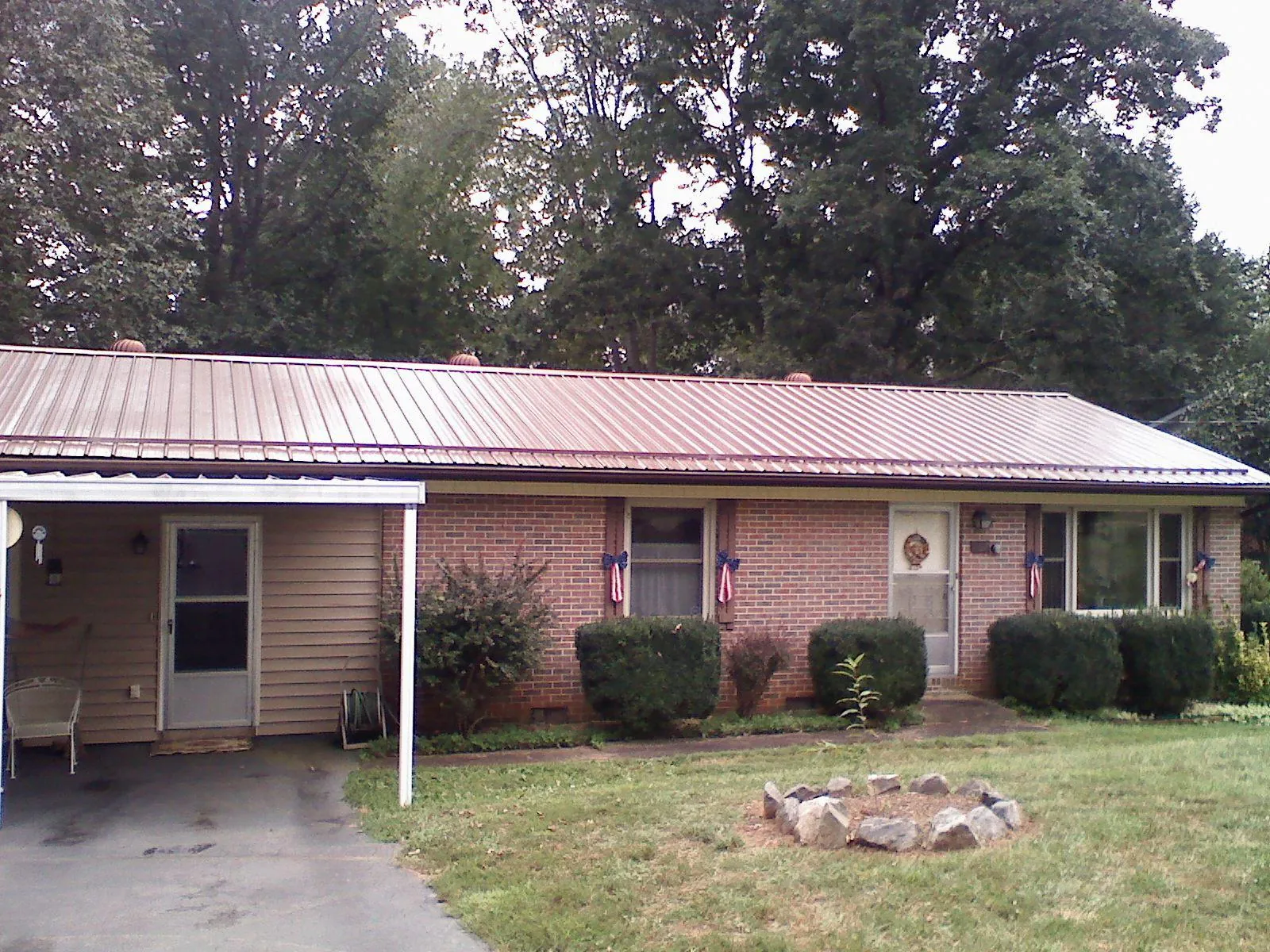 Bronze metal roof and carport on a brick ranch home — Roof Repair work by our crew in Waukee