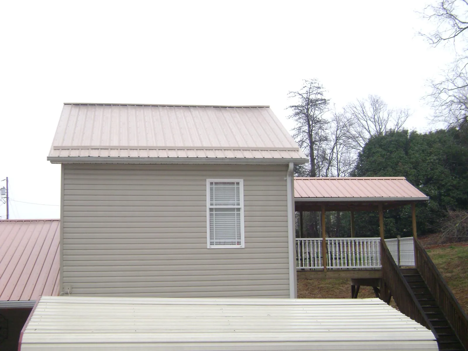 Tan metal roofs on a two story addition and attached porch, from a Roof Replacement job in Waukee